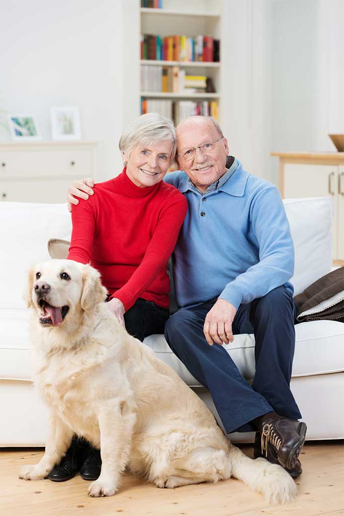 older couple sitting on a couch with a dog