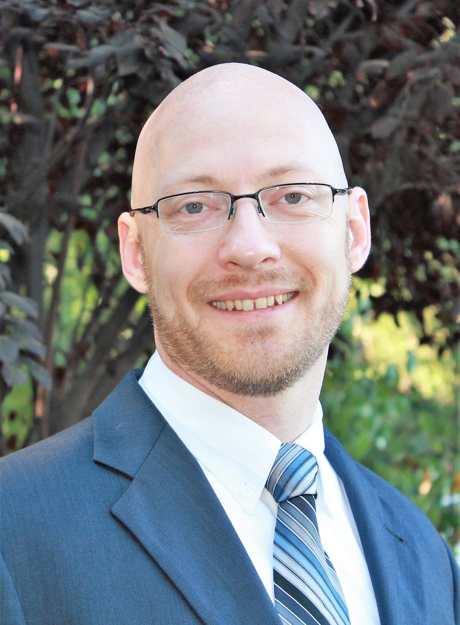 Paul Munly wearing a blue suit with a white shirt and striped tie