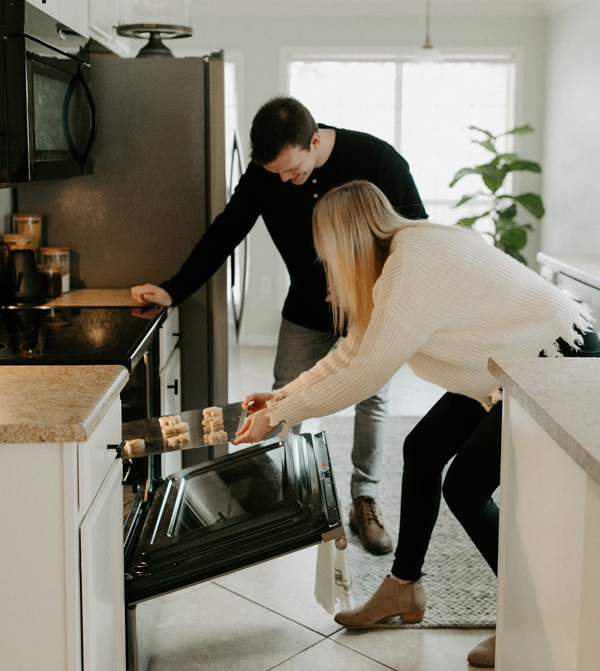 a couple putting food into their oven